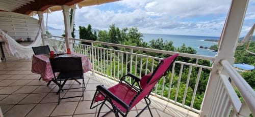 Balcon avec vue sur mer au Nid De Bellemont, Trois-Rivières Guadeloupe - chaise rouge surplombant le paysage tropical et l'océan