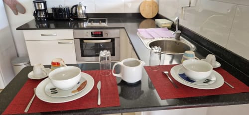 Table de petit-déjeuner élégante pour deux au gîte Le Nid De Bellemont à Trois-Rivières avec sets rouges et vue sur mer
