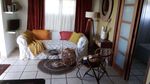 Salon cosy du Nid De Bellemont avec canapé blanc, coussins colorés, fauteuils tressés et vue sur mer à Trois-Rivières