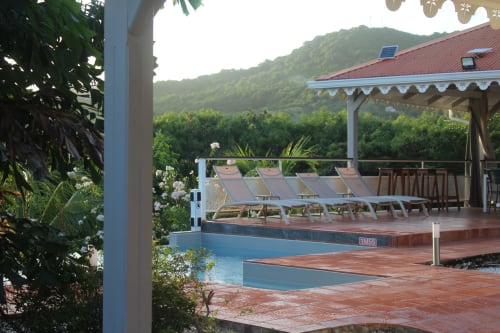 Terrasse en terre cuite avec piscine et transats face aux mornes verdoyants - Villa Bwa Kanpech Le Vauclin