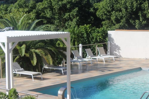 Espace détente au bord de la piscine avec pergola blanche ombragée et transats alignés - Villa Caryota.