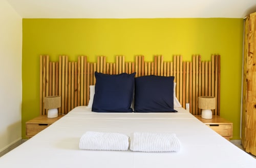 Chambre moderne climatisée avec mur vert anis, tête de lit design en bois et coussins bleu marine - Villa confort Le Marin.