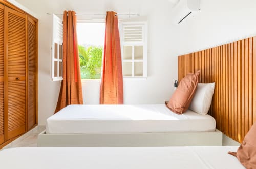 Chambre lits jumeaux lumineuse avec rideaux orange, grand dressing en bois et climatisation - Idéal enfants ou amis.