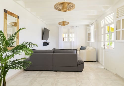 Spacieux salon lumineux au design épuré avec grands canapés confortables et luminaires en osier - Villa Caryota.