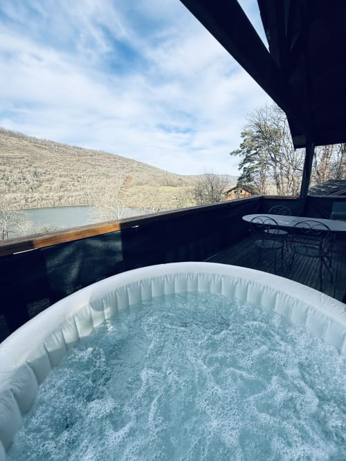 Bubbling hot tub on terrace overlooking lake and mountains at Cabanes du Belvédère lodge, Serrières-sur-Ain
