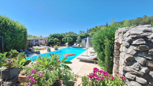 Luxury pool area at La Bergerie Du Moulin B&B in Taradeau with loungers, vibrant flowers, and hilltop views
