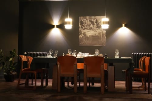 Elegant dining room at Le Petit Château B&B in Baye with orange chairs, black table, pendant lighting, and artwork.
