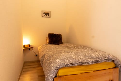 Chambre cosy aux Les Louettes B&B à Saxon avec lit en bois, parure motifs et tableau d'ours au mur