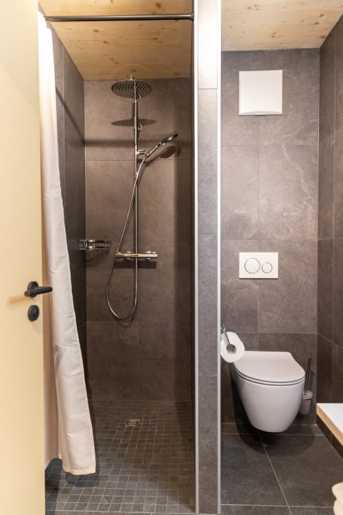 Salle de bains moderne au Chalet d'hôtes Les Louettes Saxon avec douche à l'italienne, toilettes murales et plafond en bois naturel