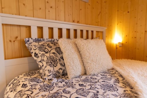Chambre douillette au Chalet d'hôtes Les Louettes à Saxon avec murs en bois, literie à motifs et éclairage chaleureux