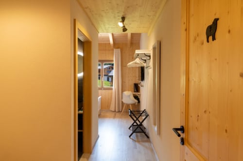 Étroit couloir en bois du gîte Les Louettes à Saxon avec murs clairs, porte-manteau et décoration minimaliste