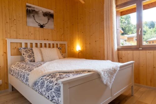 Chambre alpine douillette aux Louettes B&B à Saxon avec murs en bois, lit blanc, art cervidé et vues montagnardes