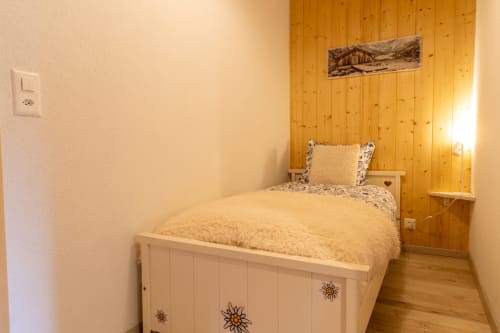 Chambre douillette au Chalet d'hôtes Les Louettes, Saxon avec murs en bois, lit simple avec parure florale et vue sur les montagnes