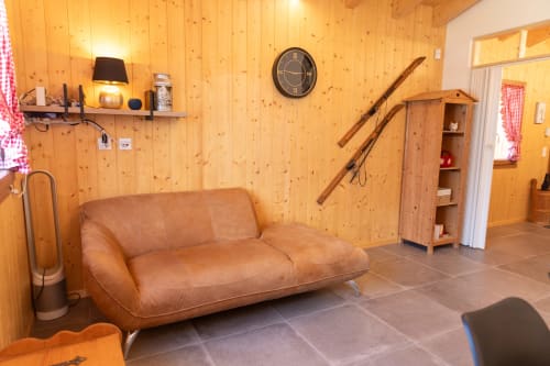 Intérieur chaleureux du chalet en bois des Louettes B&B à Saxon avec canapé en cuir cognac et équipements modernes