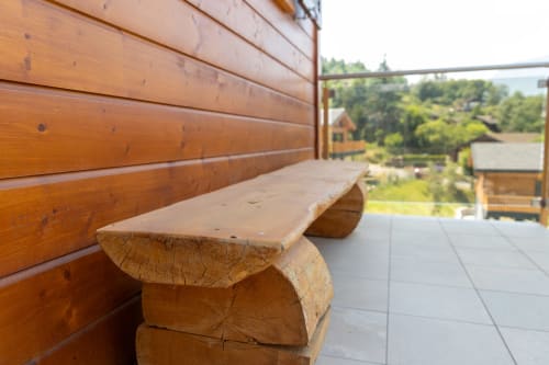 Banc en bois sur la terrasse du Chalet d'hôtes Les Louettes à Saxon, avec vue sur les montagnes et architecture rustique