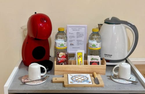 Bandeja de bienvenida en el apartamento Vermello de Holibai Baiona, con cafetera roja, hervidor eléctrico, tazas y