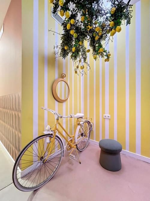 Lemon Hostel Altea lobby features yellow striped walls, hanging lemon plants, vintage bicycle, and round mirror décor.