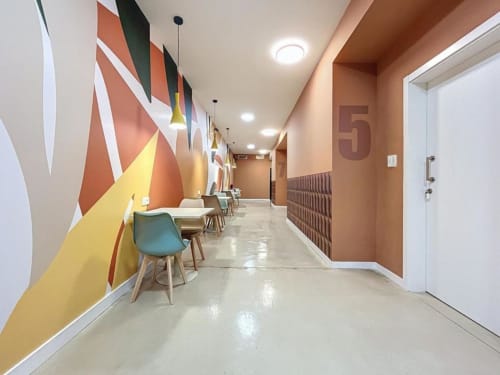 Modern hallway at Lemon Hostel Altea featuring colorful geometric wall art, pendant lighting, and numbered room doors along a