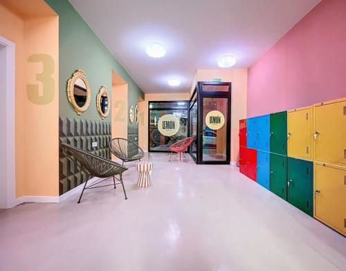 Colorful Lemon Hostel Altea common area with vibrant walls, modern chairs, numbered doors, and storage lockers