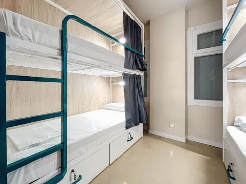 Modern dormitory room at Lemon Hostel Altea with teal bunk beds, white bedding, and shared bathroom facilities