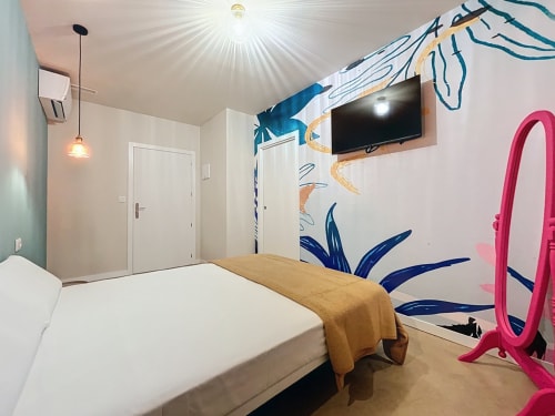 Private double room at Lemon Hostel Altea featuring modern art wall mural, white bed, pink mirror, wall-mounted TV, and