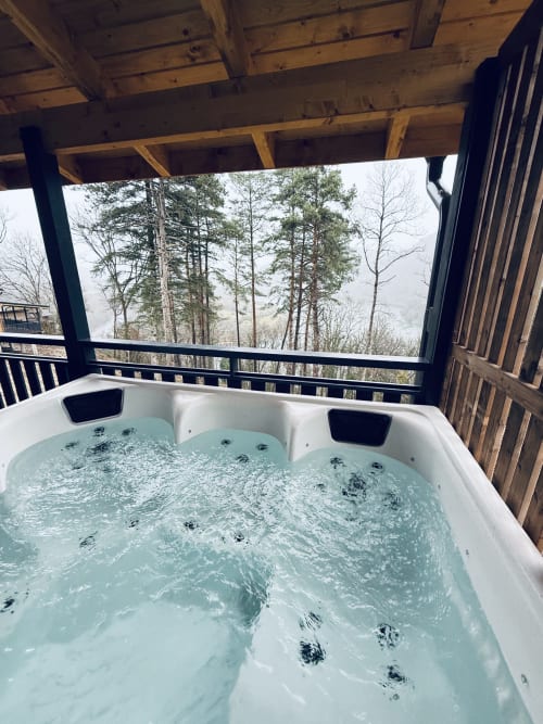 Vasca idromassaggio fumante su terrazza in legno con vista sulla foresta di pini presso Cabanes et lodges du Belvédère, Serrières-sur-Ain