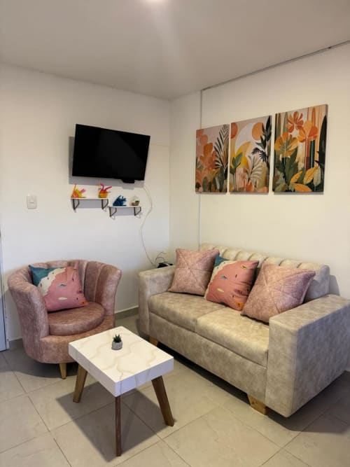Moderno salón de apartamento en Olamar Living con sofá cómodo, sillón, TV y arte botánico en la pared en Coveñas