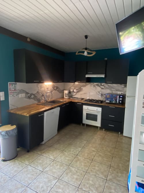 Cuisine moderne avec meubles noirs, plans de travail en bois et dosseret en marbre au Gîte villa Bagatelle