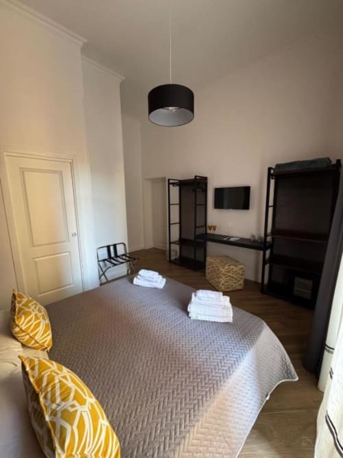 Modern bedroom at Le Boutique del Centro in Naples featuring a queen bed, black pendant light, flat-screen TV, and yellow