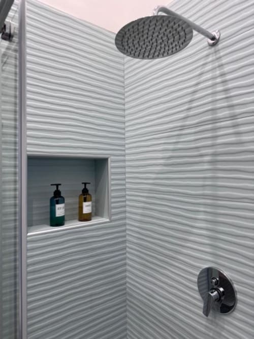 Modern shower in La Boutique del Centro hotel room with rainfall showerhead, textured tile walls, and built-in soap niche in
