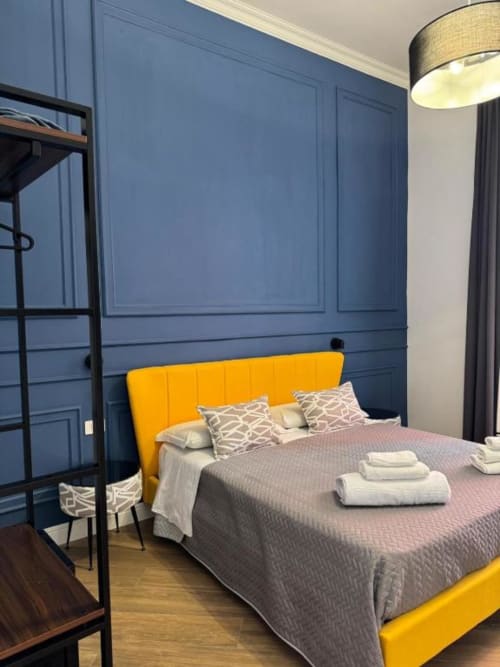 Camera moderna con testata gialla e rivestimento murale blu presso Le Boutique del Centro a Napoli