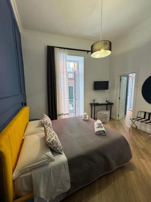 Camera moderna di Le Boutique del Centro a Napoli con testata gialla, balcone con vista sulla città e arredi contemporanei