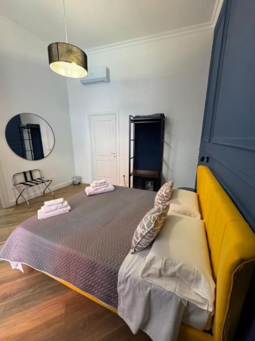 Camera moderna de Le Boutique del Centro a Napoli con letto giallo, biancheria grigia, lampada a sospensione e vista sulla città