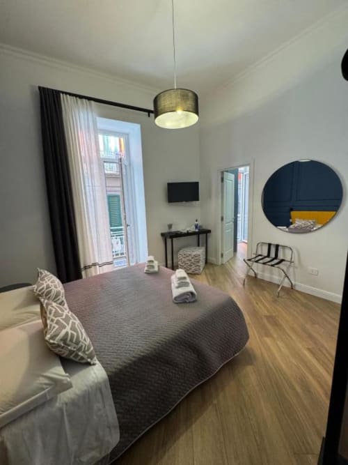 Camera moderna de Le Boutique del Centro a Napoli con letto queen, accesso al balcone, TV a schermo piatto e specchio rotondo.