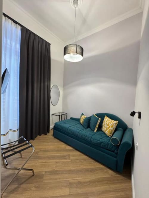 Camera moderna presso Le Boutique del Centro a Napoli con divano teal, pavimenti in legno, illuminazione a sospensione e vista sulla città