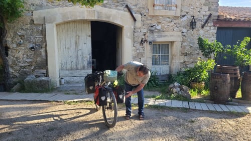 Cycliste ajustant son vélo dans la cour de la maison d'hôtes Le N°9 à Argeliers, France