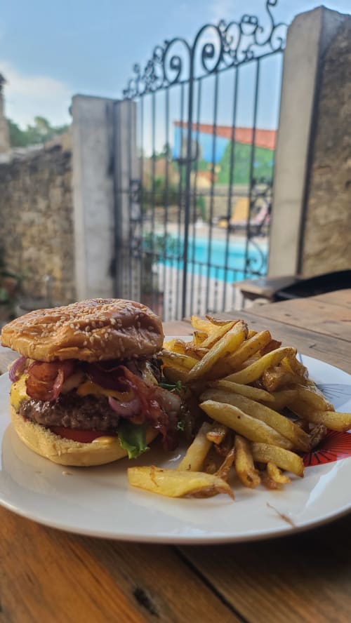 Burger gourmet avec frites croustillantes au Le N°9 BnB à Argeliers, servi au bord de la piscine devant un portail orné