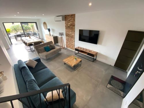 Modern living room at Villa Stella in Favone, with blue sofa, TV, brick accent wall and outdoor access managed by Corsu di Core conciergerie