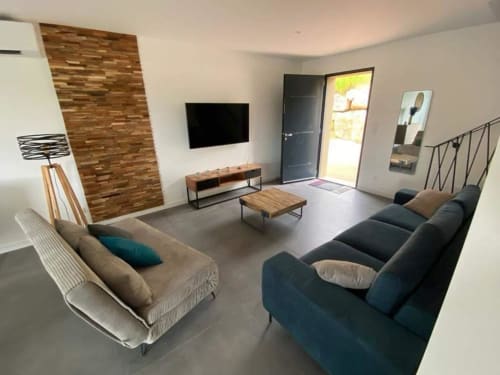 Modern living room in Stella villa at Favone with seating, wall-mounted TV, and terrace access, managed by Corsu di Core conciergerie