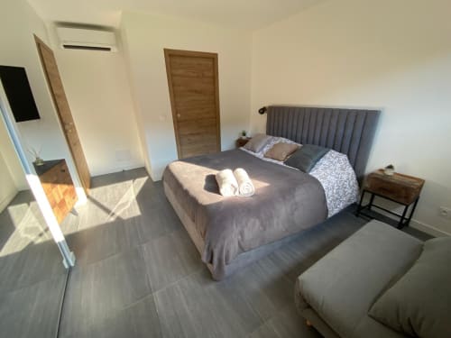 Modern bedroom in Villa Stella at Favone, featuring queen bed with gray headboard, wooden doors, and tiled, managed by Corsu di Core conciergerie