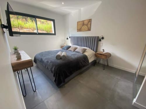 Modern bedroom in Villa Stella at Favone, with gray upholstered headboard, wooden nightstands, managed by Corsu di Core conciergerie