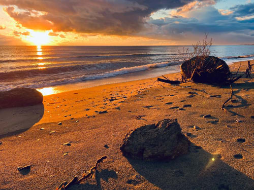 Stunning sunset over beach with waves and rocks near Favone, Corsica