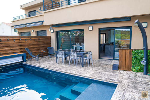 Patio piscine de la Villa Core di Favona avec piscine chauffée, espace repas et maison moderne en Corse, géré par la conciergerie Corsu di Core