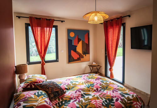 Chambre moderne de villa avec parure florale colorée, rideaux rouges et vue sur les montagnes à Centuri, Corse