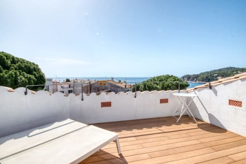 Terrassa a la teulada amb sòl de fusta, gandules blanques i vistes al mar a Calella de Palafrugell