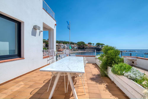Beachfront apartment terrace with sea views in Palafrugell, Spain - dining table and chairs on tile patio overlooking