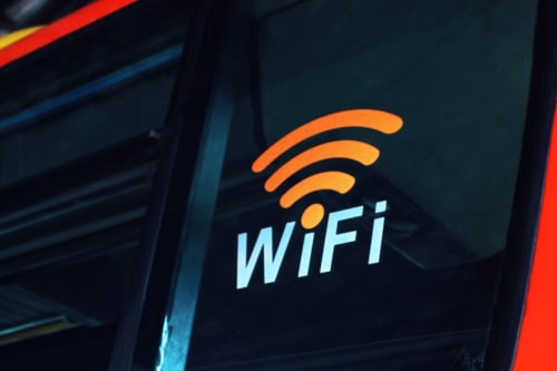 Logo WiFi avec ondes de signal orange et texte bleu clair sur écran sombre au Home Sweet Lodge Glamping Aquitaine