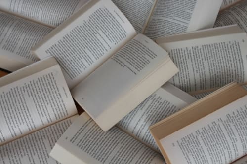 Plusieurs livres ouverts avec des pages de texte arrangés ensemble, représentant la littérature et les matériaux de lecture