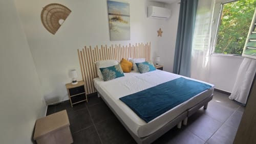 Chambre moderne à la Villa Tourmaline au Lorrain avec lit queen, tête de lit en bois, accents bleus et baies vitrées sur le jardin