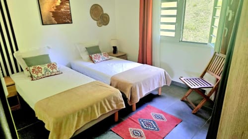 Lits jumeaux avec coussins colorés dans la chambre lumineuse de la Villa Tourmaline, Martinique, vue sur le jardin et design moderne